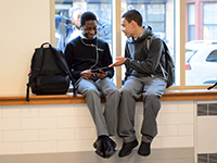 high school boys sitting in a school hallway, talking