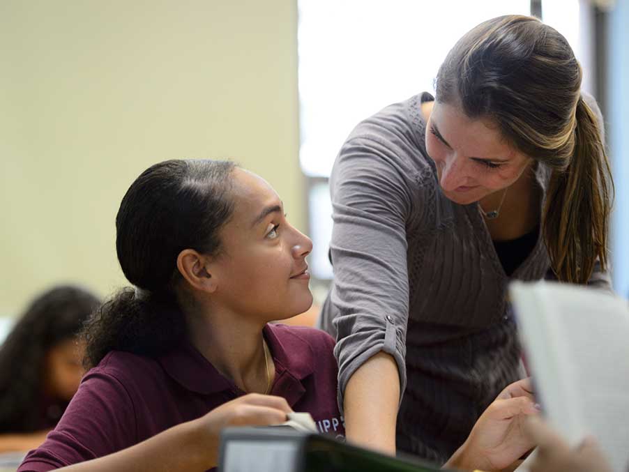 Teacher speaking to a student on a laptop in a classroom