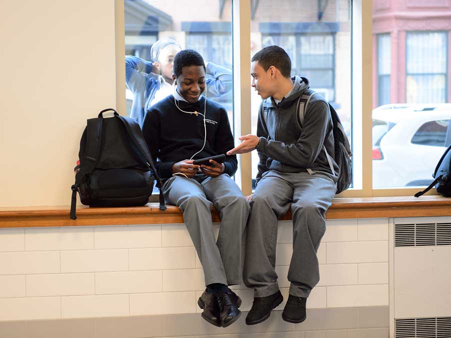 high school boys sitting in a school hallway, talking