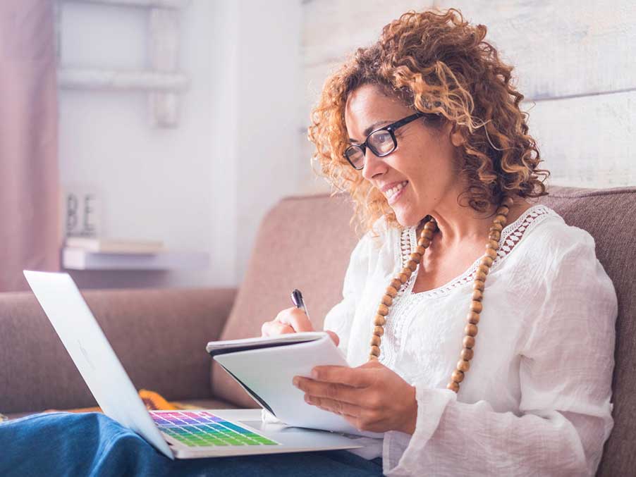 woman on a a laptop and writing on a paper notebook