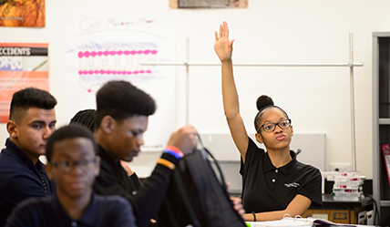 Teen female student raising her hand in a classroom