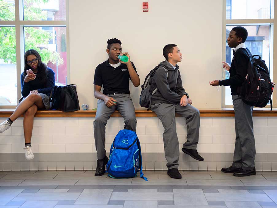 students sitting in a school hallway chatting